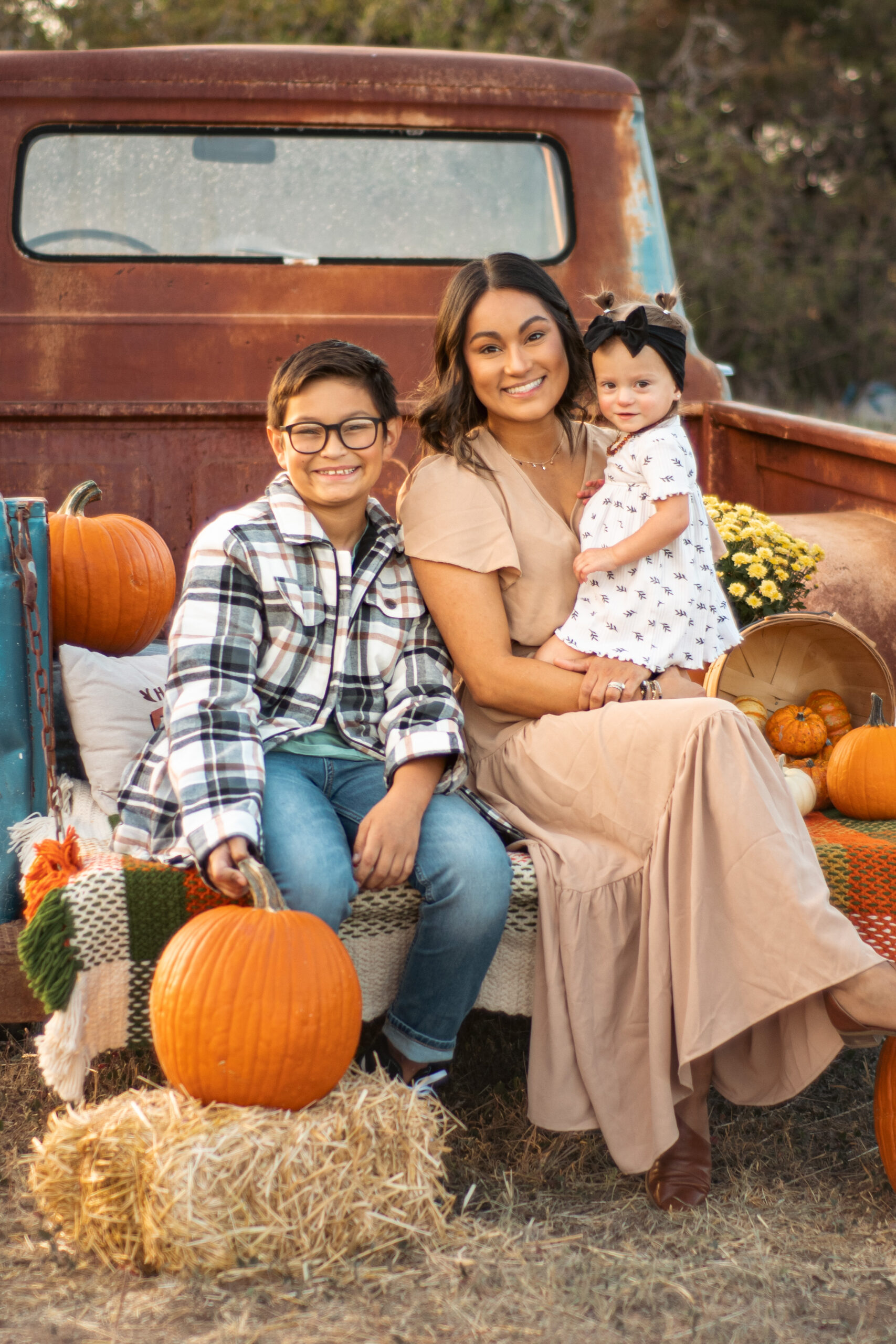 Family posing with pumpkins in the bed of a vintage truck at Heritage Urban Farm in Weatherford, Texas